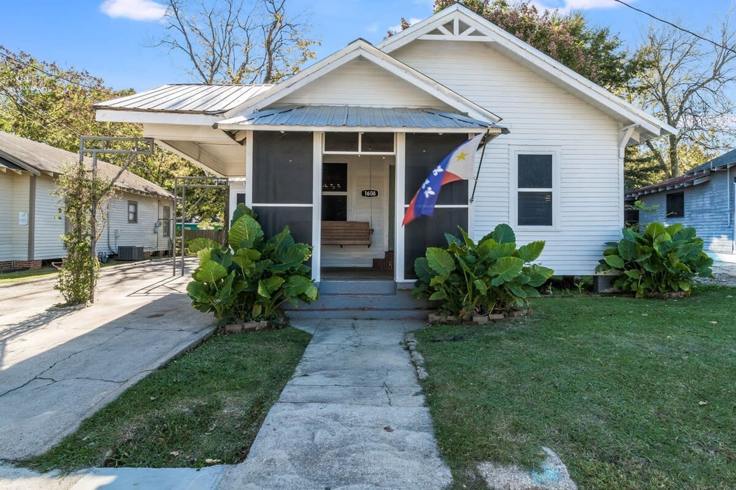 Una casa de un piso con porche delantero, una bandera y un buzón.