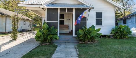 A single-story house with a front porch, a flag, and a mailbox.