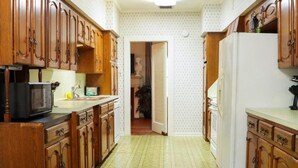 Una cocina con armarios de madera, microondas y refrigerador.