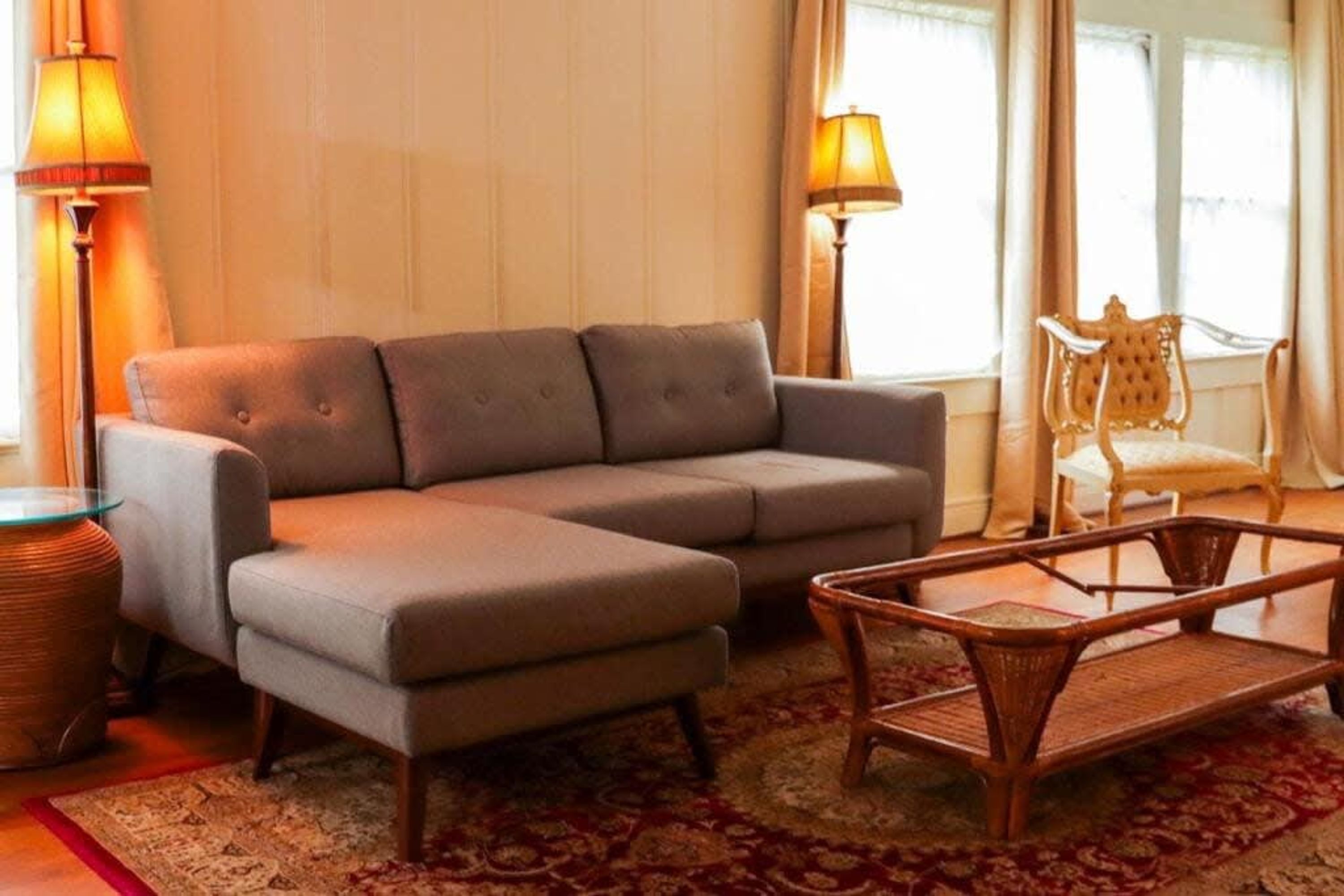 Una sala de estar con un sofá, una mesita auxiliar, una lámpara y una silla.