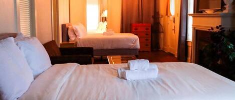 A hotel room with a large bed, a smaller bed, a desk, and a dresser.