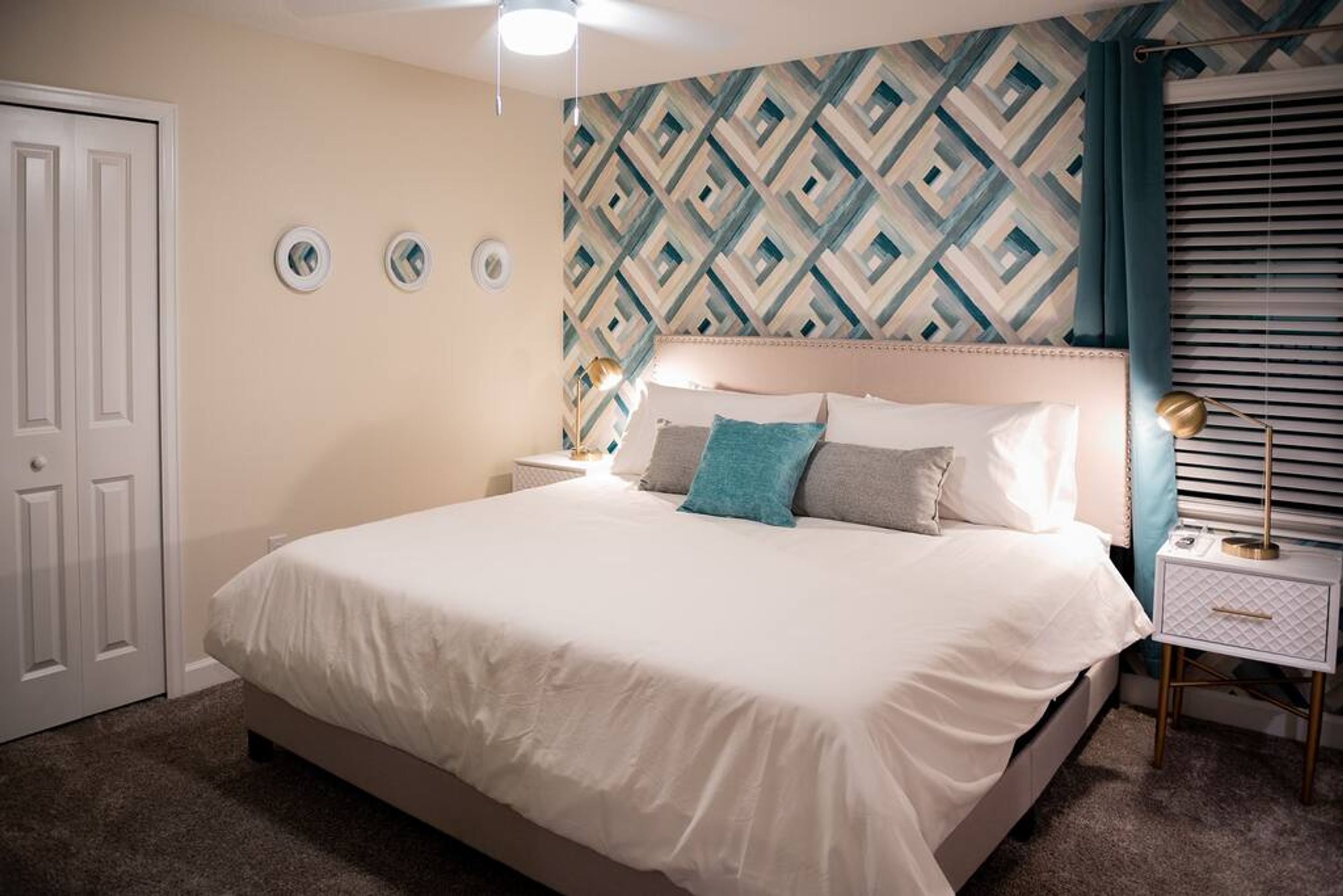A bedroom with a bed, a nightstand, a wall clock, and a door.