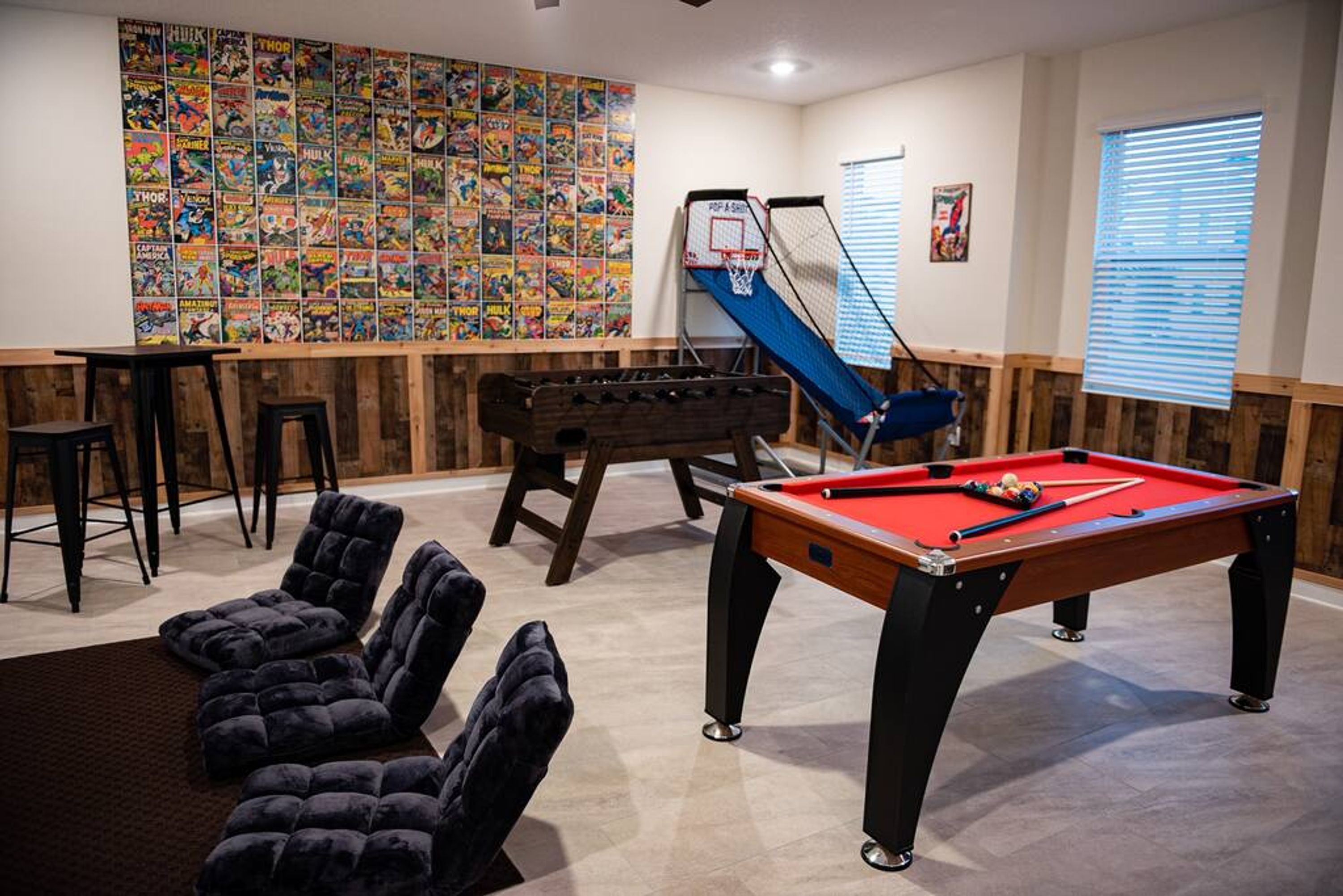 Un tavolo da biliardo, un tavolo da calcio e una parete con fumetti in una stanza con rivestimenti in legno.
