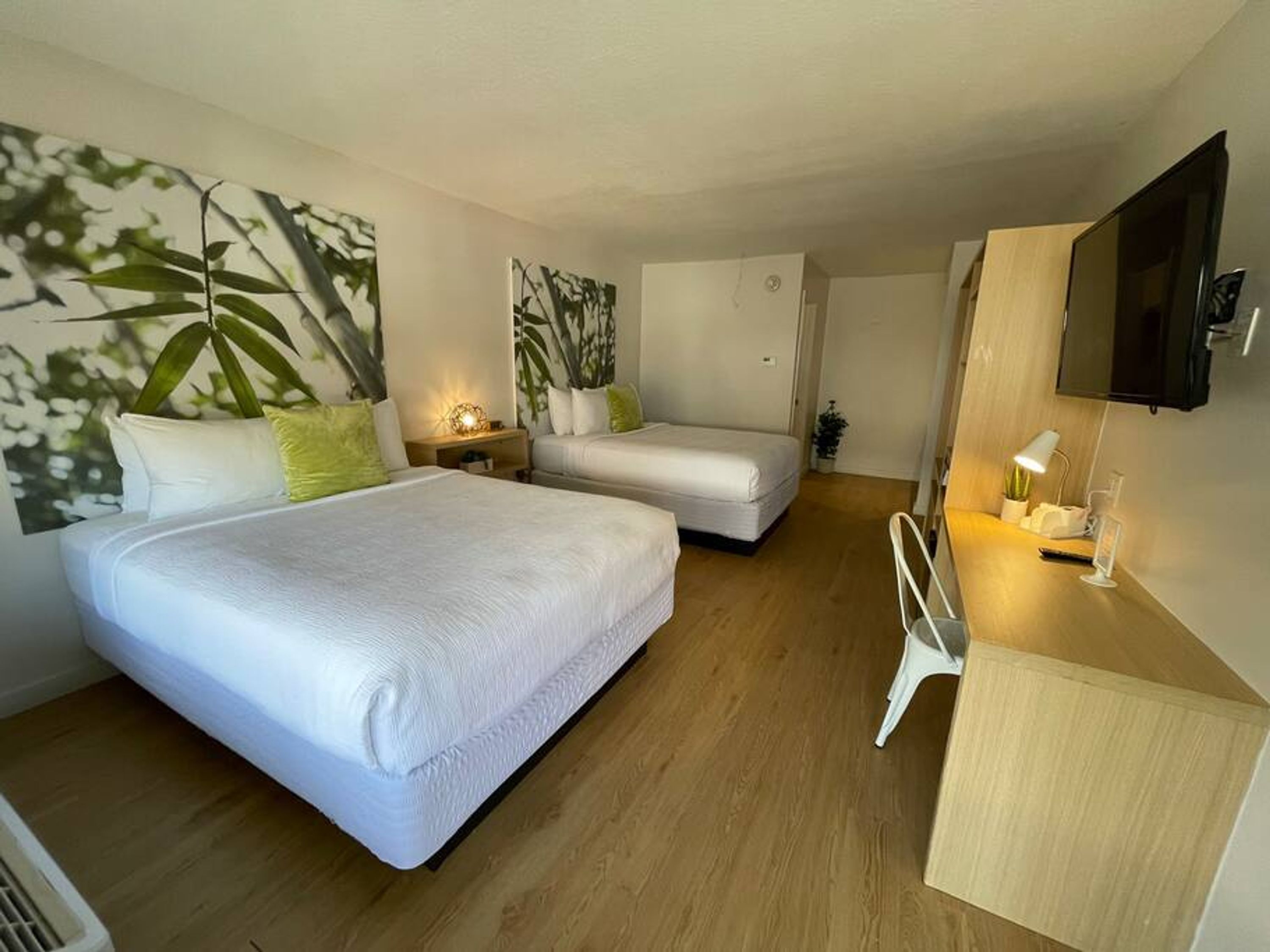 Une chambre d’hôtel moderne équipée de deux lits, d’un bureau, d’une télévision et décorée avec des œuvres d’art mural.