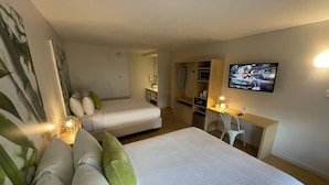 Une chambre d’hôtel moderne équipée d’un grand lit, d’un bureau, d’une télévision et d’une petite kitchenette.