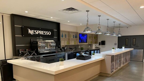 Un espace moderne dédié à Nespresso, doté d’un grand comptoir, de machines à expresso et d’un écran de télévision.