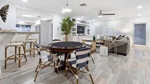 Un salon moderne avec une table à manger ronde, des chaises en osier, un canapé et un téléviseur.
