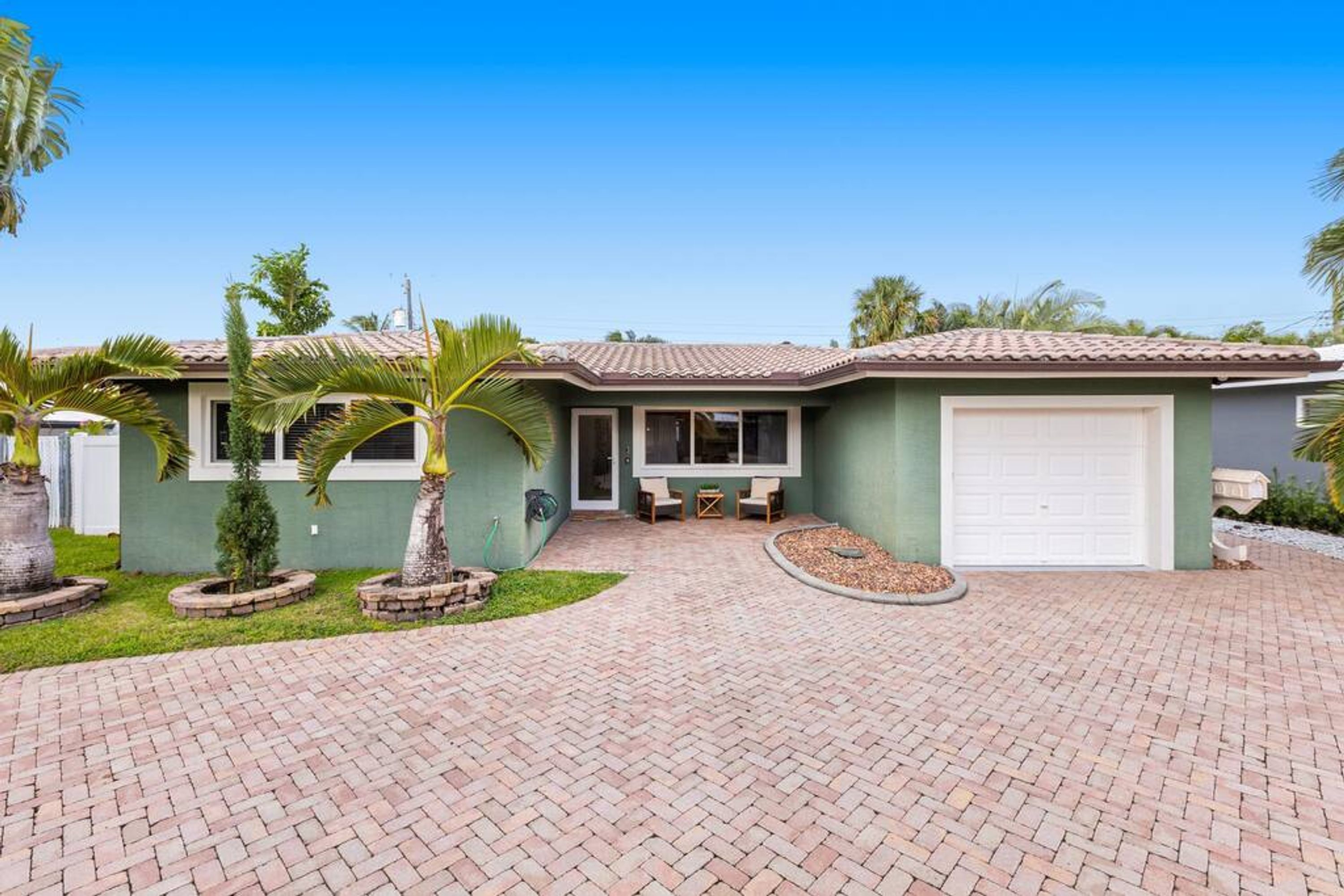 A two-story house with a tiled roof, a garage, and a paved driveway.
