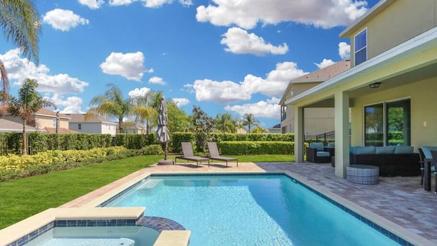 A swimming pool with a hot tub, surrounded by a well-maintained lawn and palm trees. - Luxurious Villa 9br Encore Resort Near to Disney (Kissimmee)