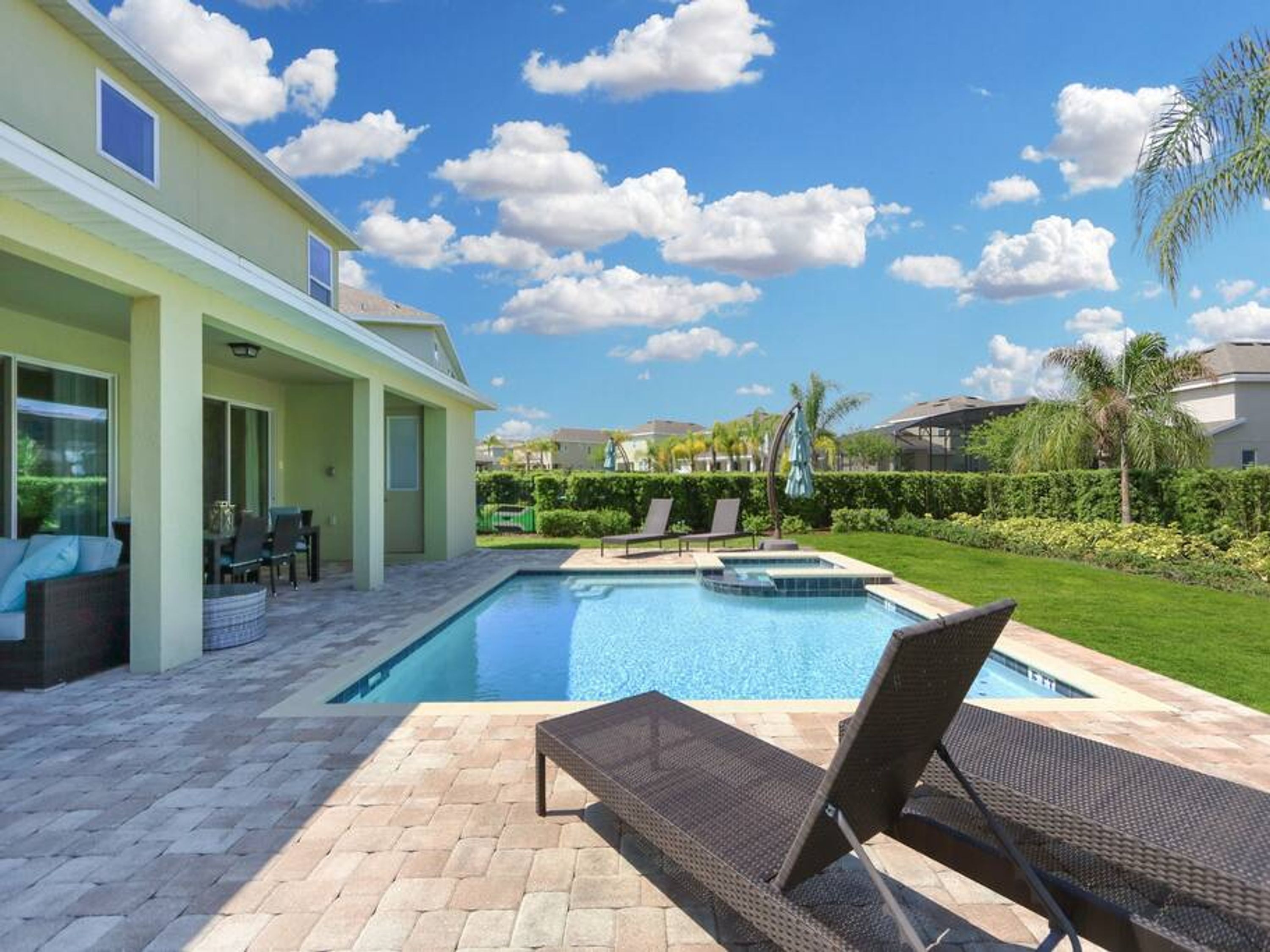 Ein Swimmingpool mit Liegestühlen, einer Terrasse und Blick auf benachbarte Häuser.