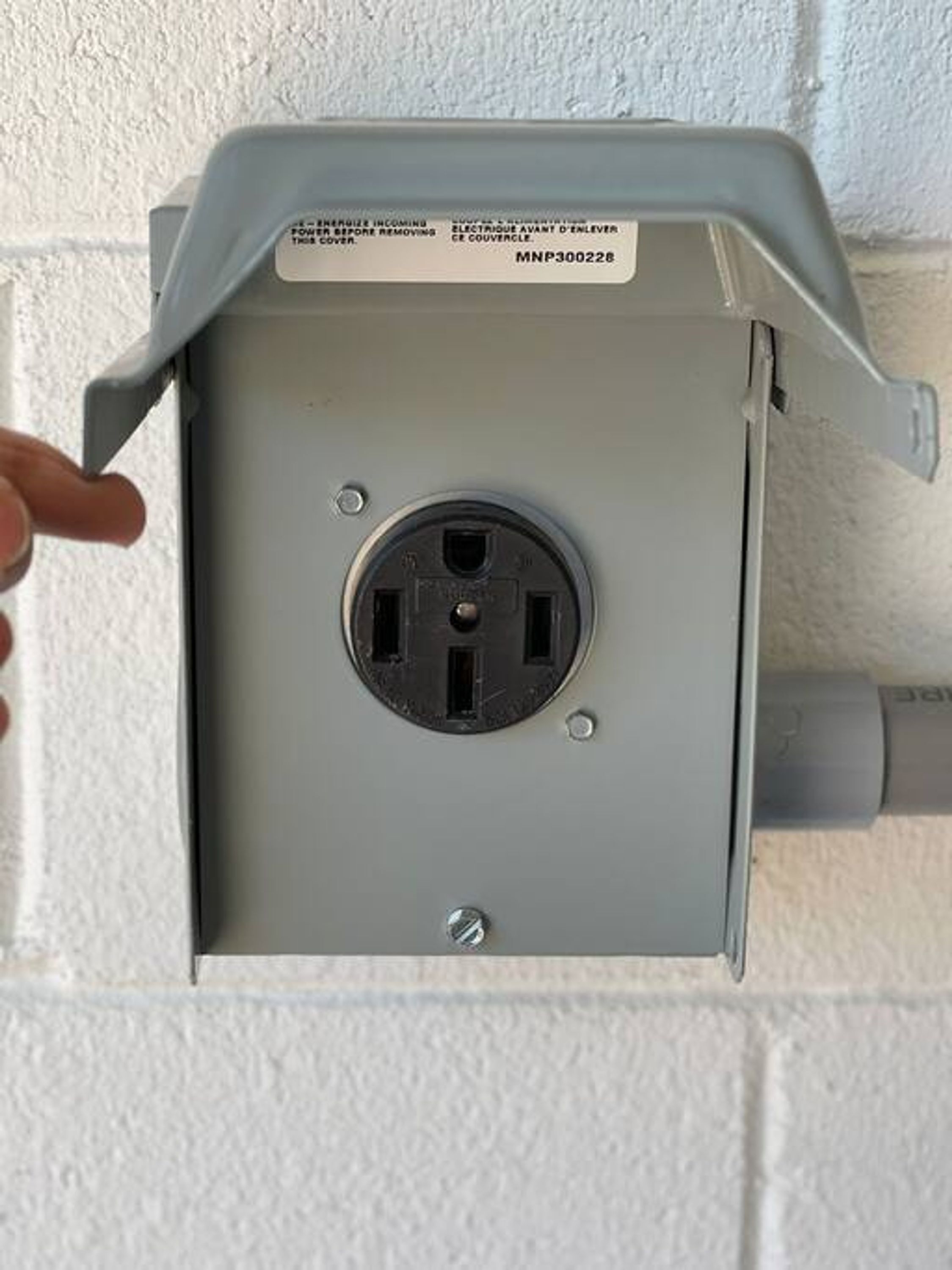A grey electrical box with a visible socket and a label with text.