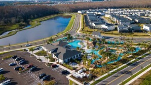 An aerial view of a residential area with a large swimming pool, multiple houses, and a parking lot. - SL 4Br Walking Distance to Club (Kissimmee)