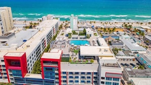 Um hotel à beira-mar com piscina no terraço, vista para o oceano e arquitetura moderna.
