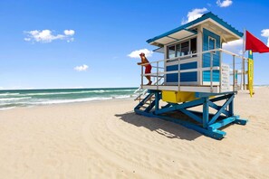 Uma torre de salva-vidas numa praia com céu claro e mar calmo.
