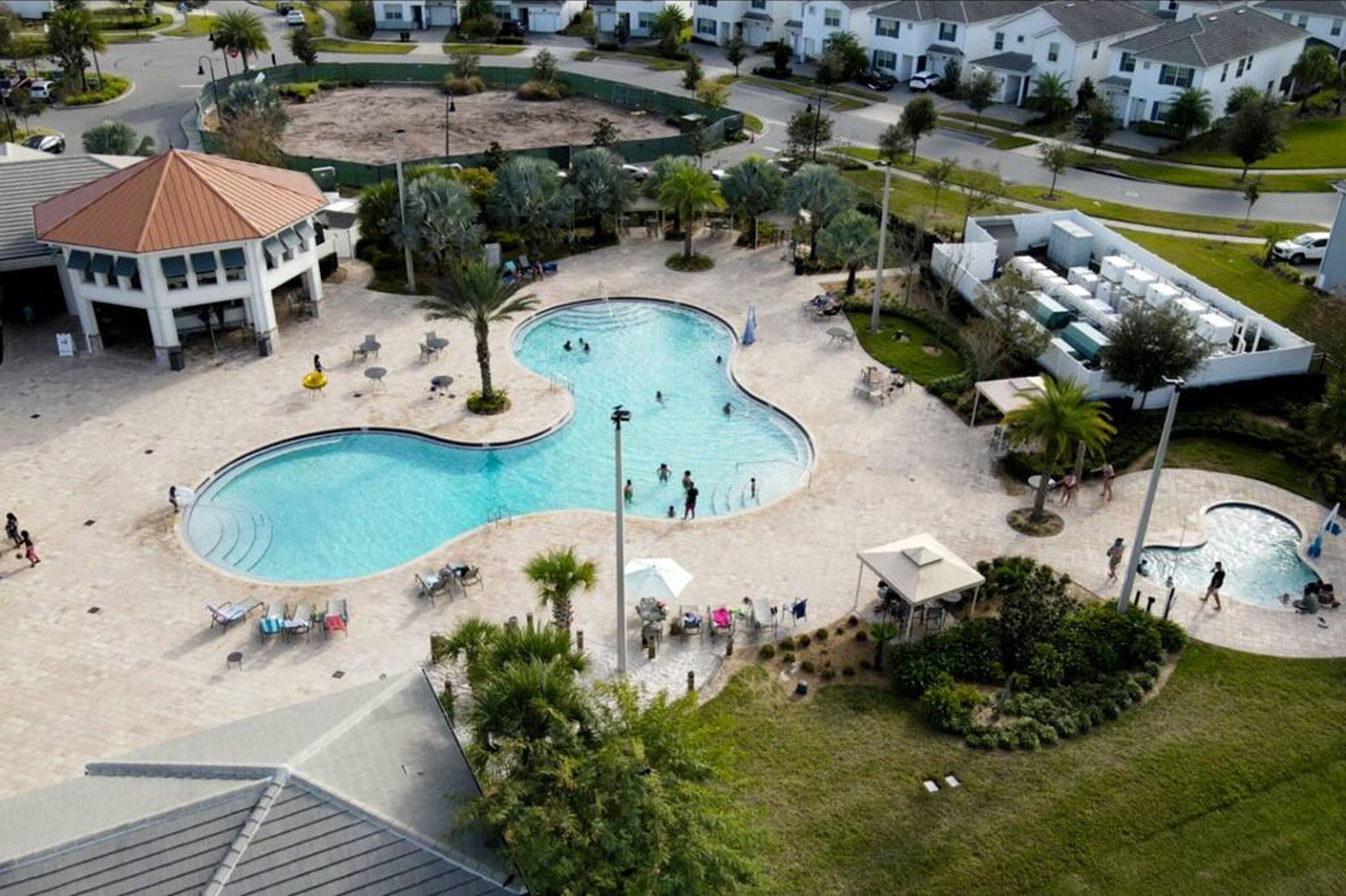 Vista aérea de un resort con una piscina central grande, varias piscinas más pequeñas y un pabellón.