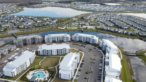 Zona residencial con modernos edificios de apartamentos, una piscina central y un lago.