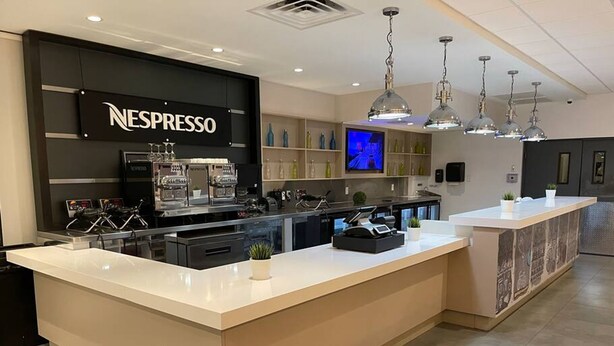 A modern kitchen with a Nespresso station, a large island, and pendant lighting. - Cozy Hotel With Super Location Near Disney (Kissimmee)
