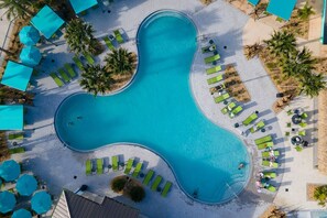 An aerial view of a swimming pool with a unique shape surrounded by green lounge chairs and umbrellas. - TH 4Br Walking Distance to Club (Kissimmee)