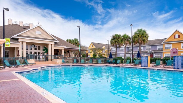 A swimming pool with lounge chairs and a building with a clock. - Enchanted Townhome Near Disney Parks 3Br (Kissimmee)
