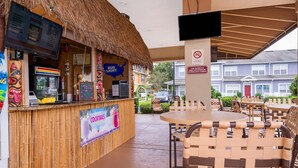 An outdoor bar area with a thatched roof, a menu board, and a sign indicating surveillance. - Enchanted Townhome Near Disney Parks 3Br (Kissimmee)