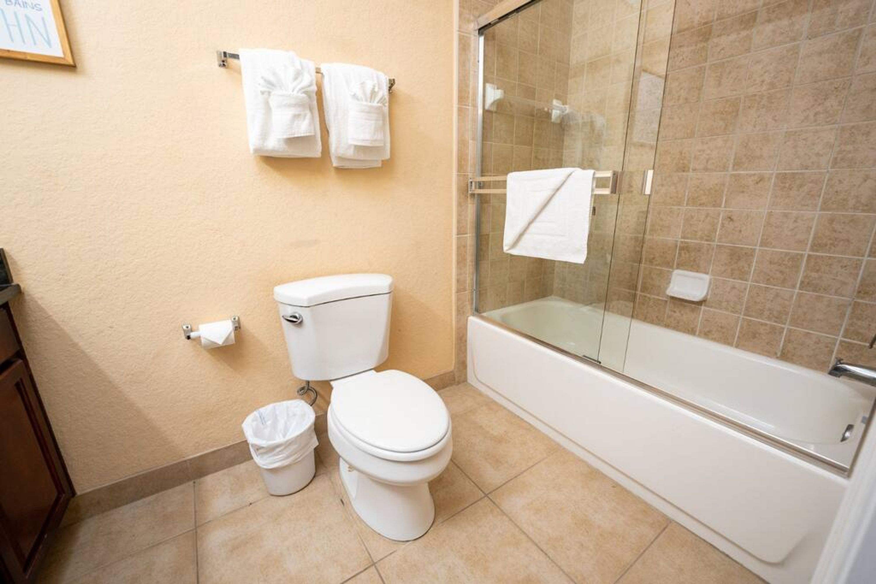 Un baño con inodoro, ducha envuelta en vidrio y bañera.