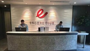 Un mostrador de recepción con dos empleados, computadoras portátiles y el logotipo de Encore Club.