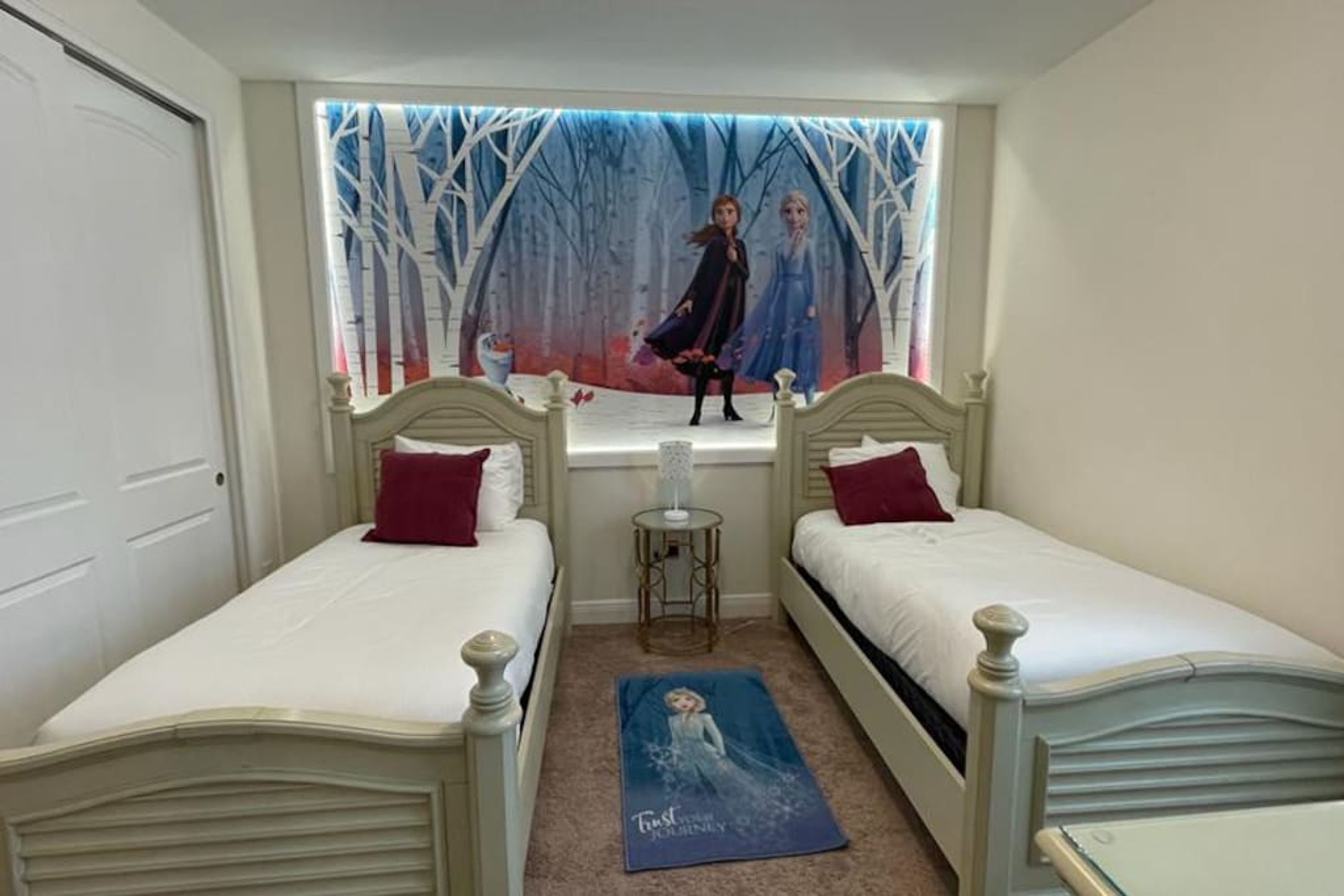 Un dormitorio con dos camas individuales, una ventana con un mural temático de bosque y un cartel en el suelo.