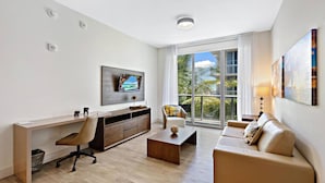A modern living room with a desk, a sofa, and a TV mounted on the wall. - Amazing Condo in Hollywood Beach (Hollywood)