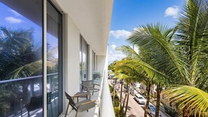 A balcony with a view of palm trees and parked cars. - Amazing Condo in Hollywood Beach (Hollywood)