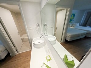 A modern bathroom with a large mirror, two sinks, and a shower. - Impeccably Clean and Cozy Hotel Room (Kissimmee)