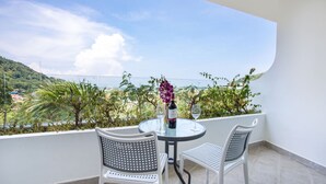 Un balcón con una mesa redonda y dos sillas, con vistas a un paisaje con vegetación y edificios.