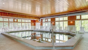 Una piscina interior con paneles de madera y ventanas amplias.