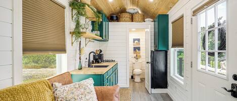 A compact kitchen with wooden cabinets, a sink, and a black refrigerator.