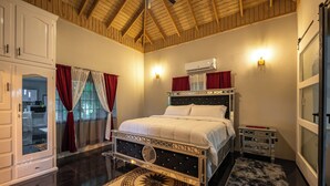 A bedroom with a bed, a nightstand, an air conditioning unit, and a view of the outside. - One Love Guesthouse (Montego Bay)