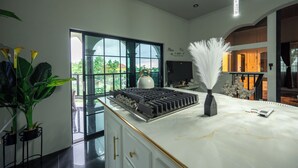 A modern kitchen with a large window, a gas stove, and decorative plants. - One Love Guesthouse (Montego Bay)