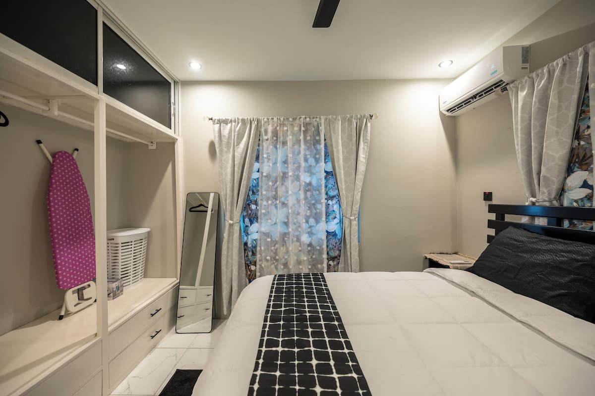 Ein Schlafzimmer mit Bett, Kleiderschrank, Spiegel und Klimaanlage.