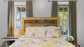 A bedroom with a wooden headboard, floral bedding, and curtains.