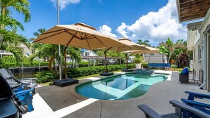 A swimming pool with lounge chairs and umbrellas, surrounded by palm trees and a view of a residential area. - Waterfront, Boat Dock, Kayaks, Fishing, Pool, Spa. 4BR / 9Beds / Sleeps14 (Palmetto)