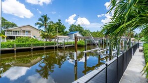 A canal with a wooden dock, surrounded by greenery and houses. - Waterfront, Boat Dock, Kayaks, Fishing, Pool, Spa. 4BR / 9Beds / Sleeps14 (Palmetto)