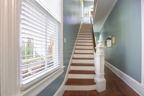Eine Treppe mit weißen Balustraden und einem weißen Geländer, die zu einer Empore mit einem Bilderrahmen führt.