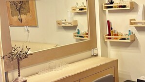 A modern bathroom with a vanity, mirror, and shelves for toiletries. - Artistic 2-bedroom apartment in green & peaceful Vari (Vari)
