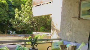 An outdoor seating area with a sofa, a table, and a potted plant. - Artistic 2-bedroom apartment in green & peaceful Vari (Vari)