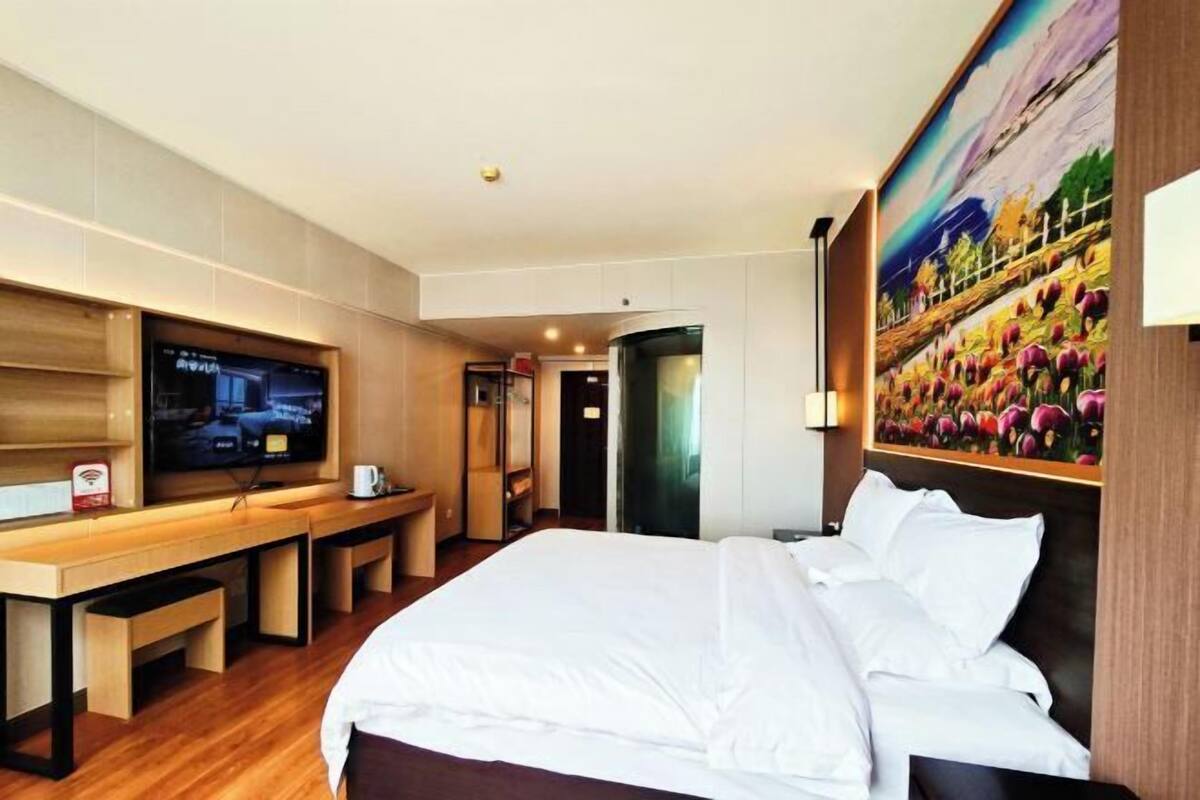 Une chambre d’hôtel avec un lit, une télévision, un bureau et un tableau au mur.