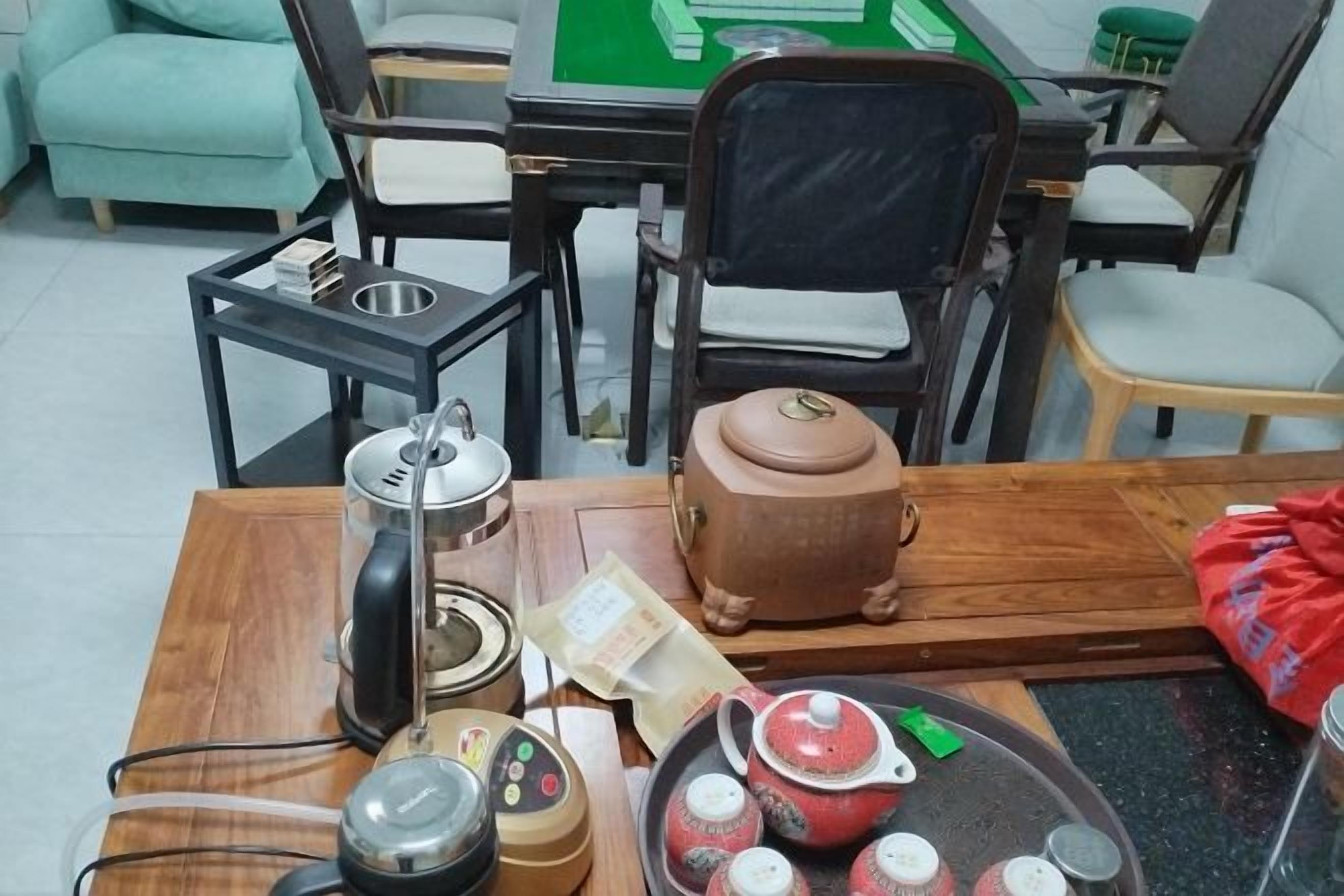 A wooden table with a kettle, teapot, cups, and a tray.