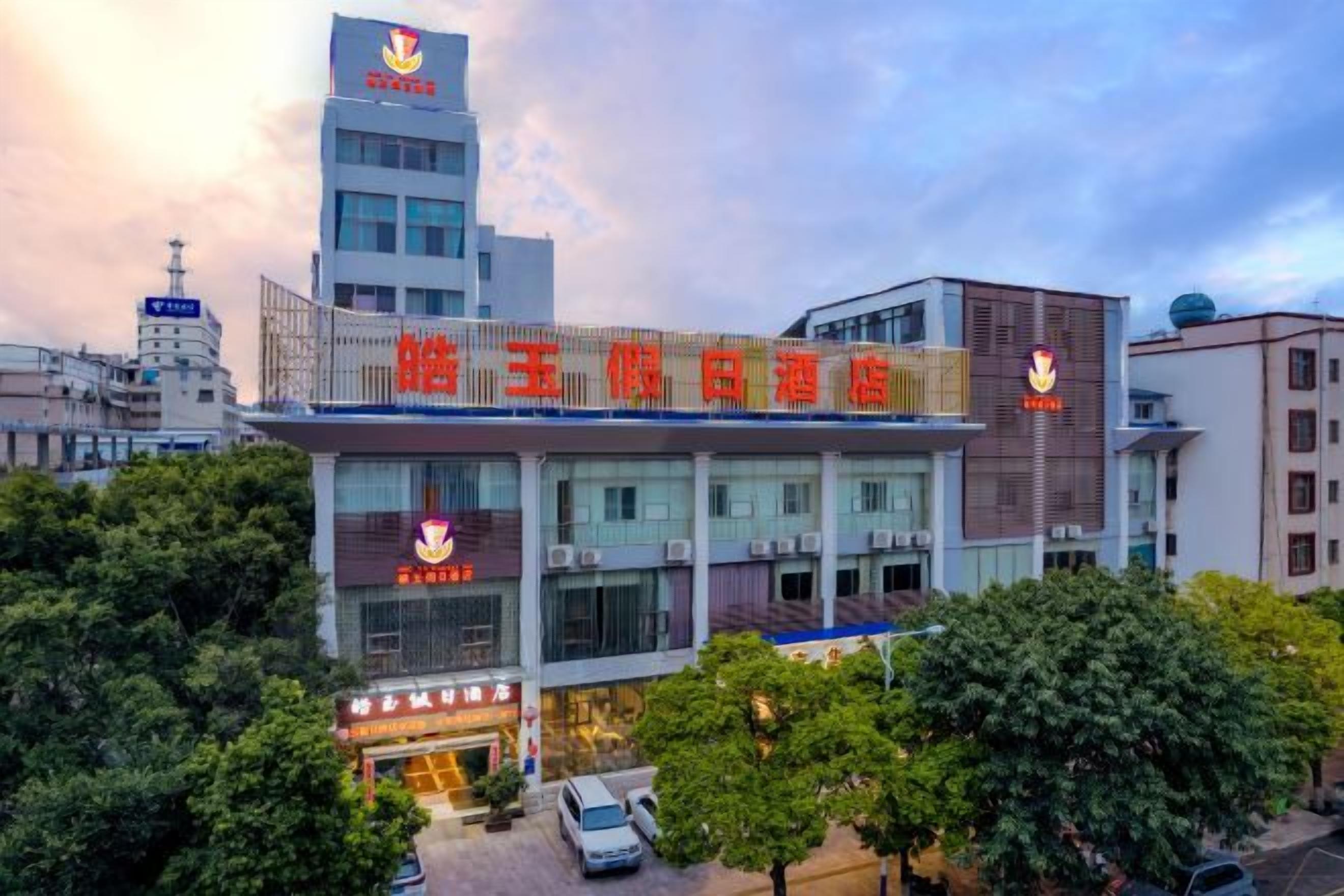 A hotel with a prominent sign, multiple floors, and a parking area.