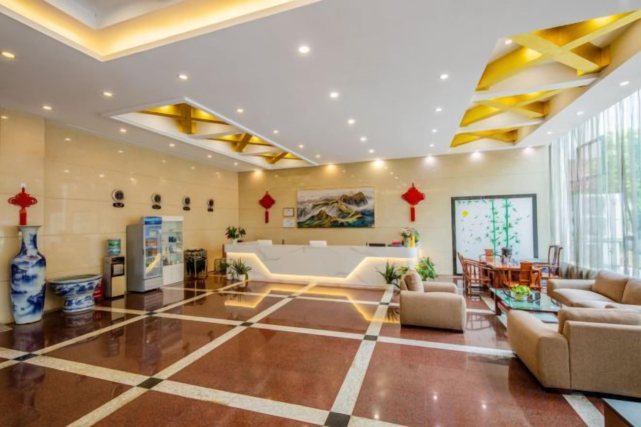 A hotel lobby with a reception desk, seating area, and a large window.
