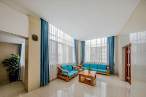 A modern hotel room with a large window, a sofa set, a wooden coffee table, and a potted plant. - Chuxiong Yuyu Holiday Hotel (Chuxiong City)