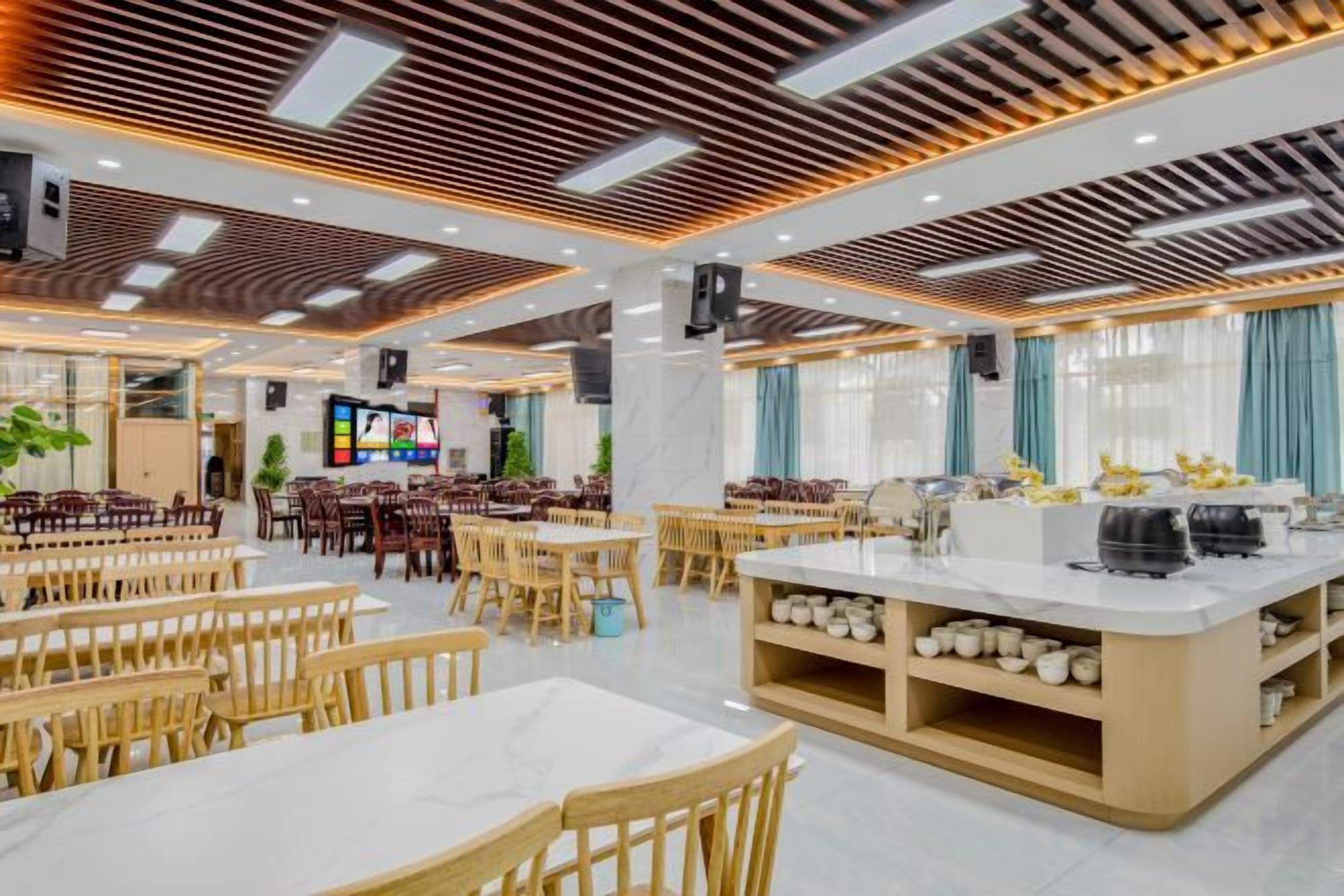 Un comedor amplio con varias mesas y sillas, una isla central con fregadero y una pantalla de televisión.