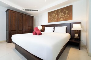 Een hotelkamer met een groot bed, een houten kledingkast en een decoratief wandobject.
