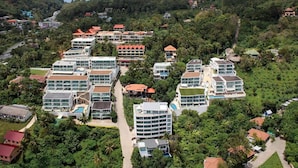 Ein Resort mit mehreren Gebäuden, darunter ein großes Hotel mit Schwimmbad und ein kleineres Gebäude mit rotem Dach.
